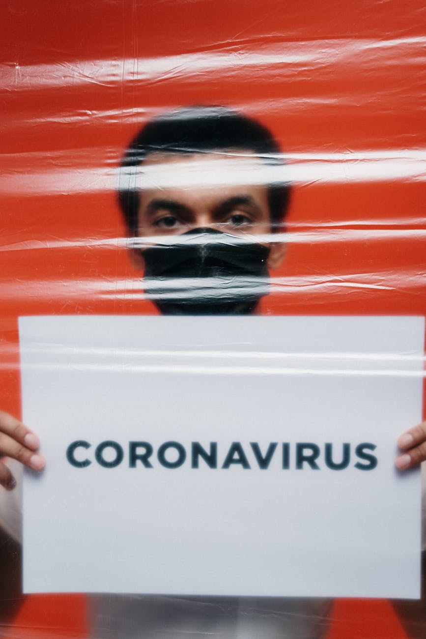 man with face mask holding a poster with coronavirus text